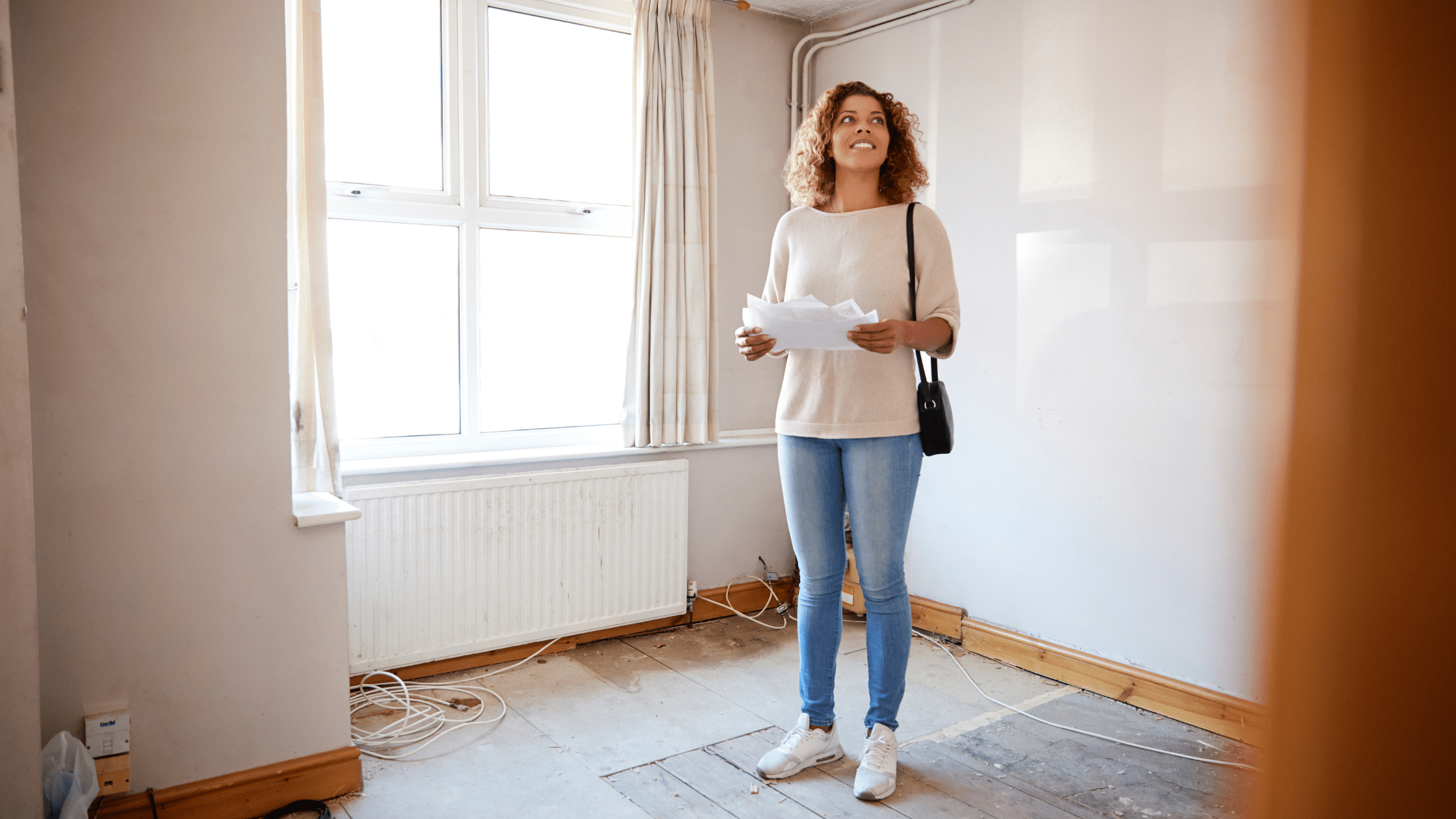 A woman with a first time mortgage standing inside a house and holding a document.