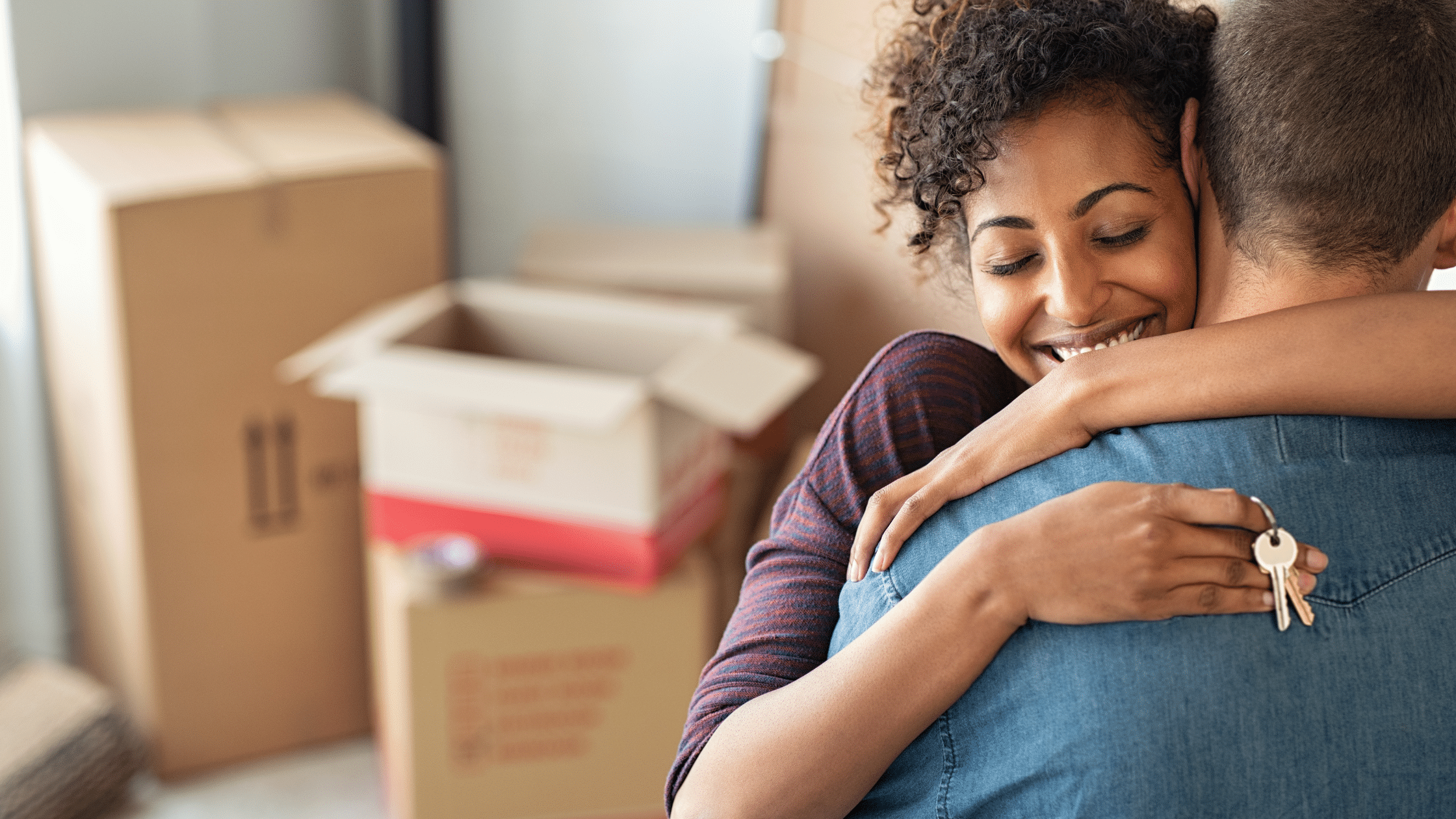 The topic, home buying tips, is presented with a woman holding her key to her newly bought house while hugging her partner.
