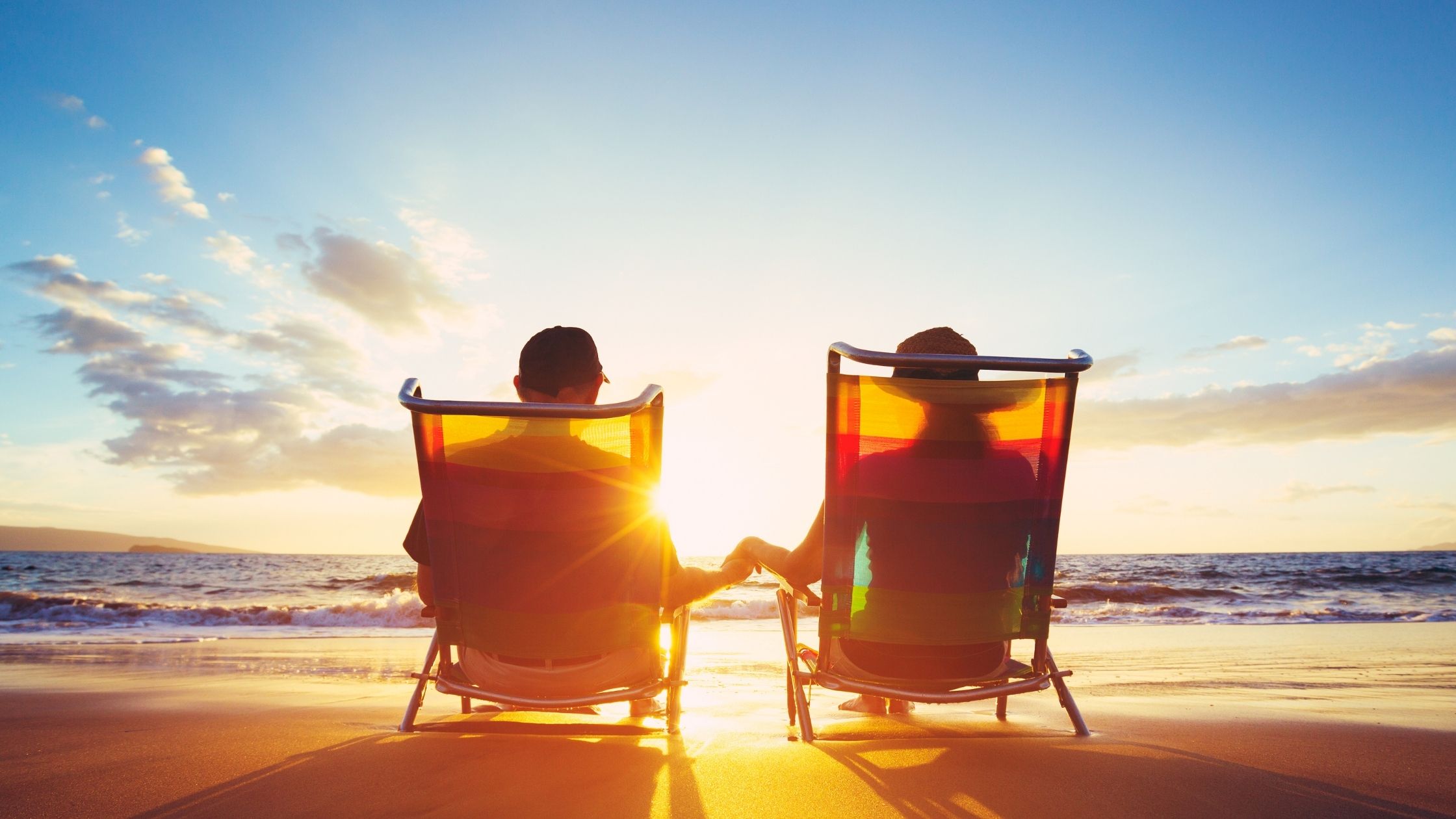 Couple relaxing in beach chairs watching sunset - the perfect retirement goal achieved through catch up retirement contributions.